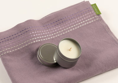 a candle in a tin box on top of a yoga wrap