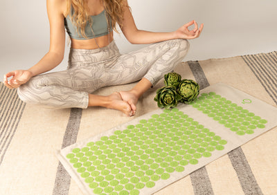 Woman sitting next to a beige and green spike mat.