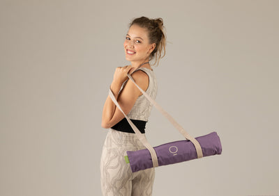 A woman holding a rolled purple spike mat. 